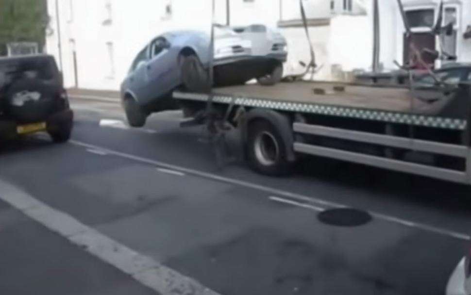 Homem retira seu carro de caminhão reboque sem usar rampa