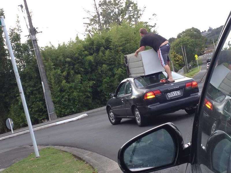 Jovens se arriscam ao transportarem geladeira na capota de carro