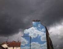 Artista de rua chama atenção pintando céus e nuvens em edifícios