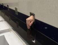 Passageiro leva enorme susto ao ver mão humana surgir em parede de urinol dentro de banheiro de aeroporto