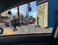 Imagem de jovem mulher ignorando morador de rua para tirar foto na frente de muro causa polêmica