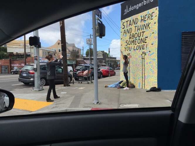 Imagem de jovem mulher ignorando morador de rua para tirar foto na frente de muro causa polêmica