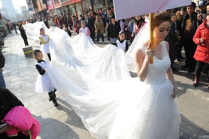 Modelo chama atenção ao caminhar com vestido de noiva de 101 metros de comprimento